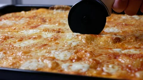 Cutting pizza into pieces using a round cutter knife, Delicious pizza Margarita Stock Footage 145373170