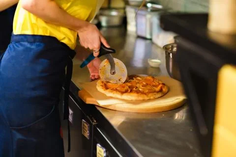 Cutting a pizza with a round knife 스톡 사진