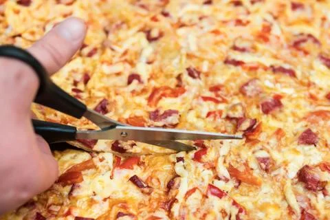 Cutting pizza with scissors Stock Photos