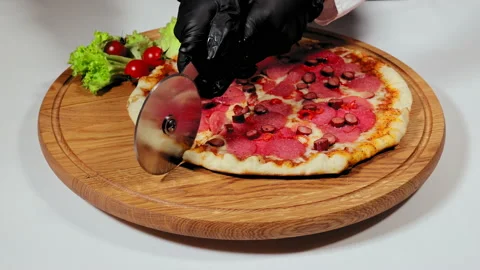 Cutting pizza into triangles with pizza cutter wheel on wooden cutting board Stock Footage 176452039