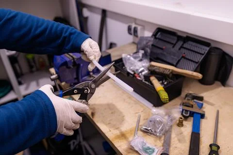 Cutting Plastic Cable Duct with Metal Shears on Workbench, Preparing Installatio Foto stock
