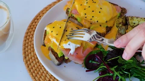 Cutting poached egg on toasted bread with avocado and salmon Stock Footage 140209154