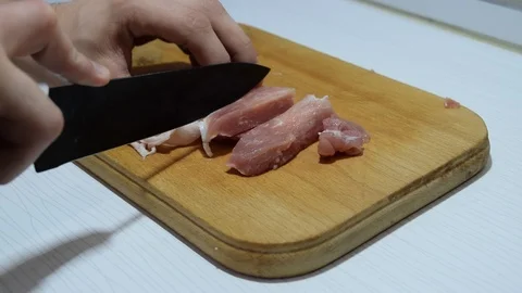 Cutting pork in the kitchen on a cutting board with a knife Stock Footage 109494844