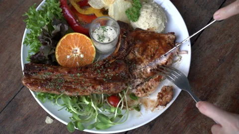Cutting Pork t-bone with knife and fork meat and bone steak with salad and ma Stock-Footage 200780647