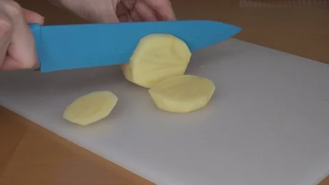 Cutting potato. Woman's hands cut potato with blue knife Stock Footage 88880889
