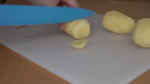 Cutting potato. Woman's hands cut potato with blue knife Stock Footage 88880937
