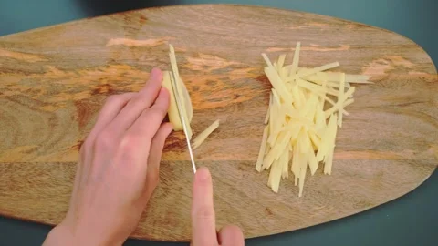 Cutting potatoes into small pieces on a cutting board Stock Footage 252374016