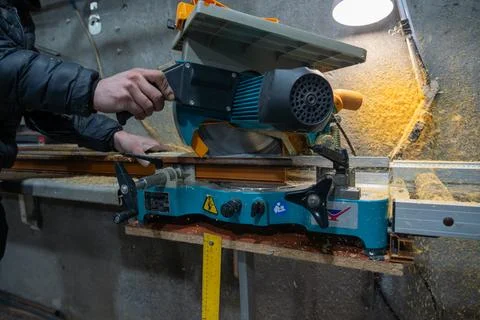 Cutting PVC window frame profile with electric miter saw in fabrication workshop Foto stock