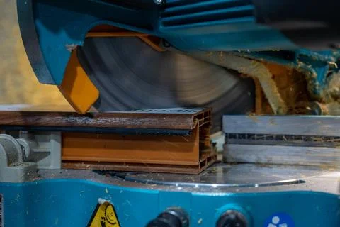 Cutting PVC window frame profile with electric miter saw in fabrication workshop Stock Photos