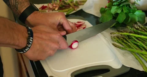 Cutting a radish into slices on a chopping board in slow-motion Stock Footage