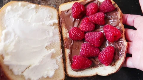 Cutting a raspberry, chocolate and cream cheese sandwich in half Stock Footage 95195997
