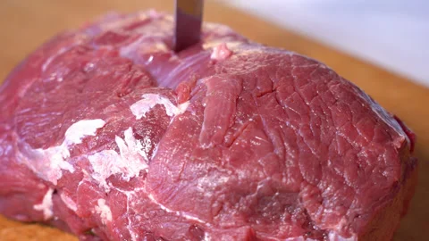 Cutting raw beef on a cutting board closeup Stockbeeldmateriaal 250550720