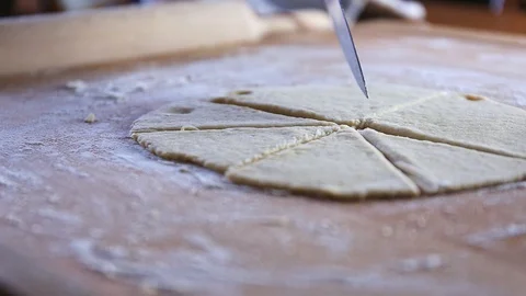 Cutting raw dough to triangles with a knife on a wooden board covered with flour Stock Footage 128693187
