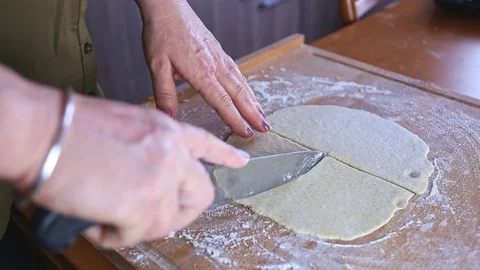 Cutting raw dough to triangles with a knife on a wooden board time lapse Stock Footage 128801393