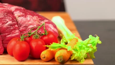 Cutting raw meat. The cook cutting raw meat on a wooden board with a knife. 動画素材 136975091