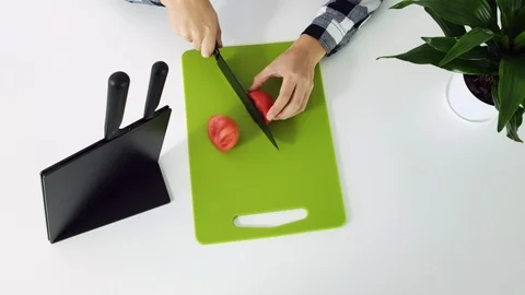 Cutting red tomatoes with kitchen knife on green board, white background, close Stock Footage 102891184