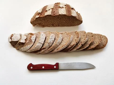 Cutting rye bread in a row and a knife on a white background Stock Photos