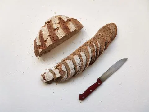 Cutting rye bread in a row and a knife on a white background Foto stock