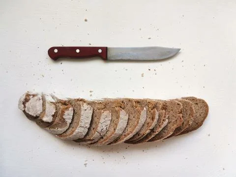 Cutting rye bread in a row and a knife on a white background Stock Photos