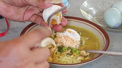 Cutting Salted Duck Egg Into A Bowl Of Indonesian Chicken Soup Stock Footage 340046455