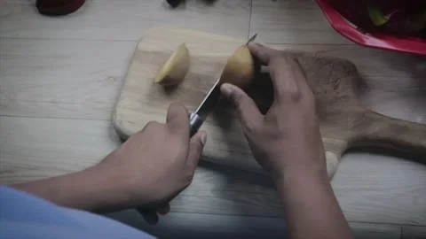 Cutting an sapodilla with a knife. The chef cuts the sapodilla on a cutting boar Stock Footage 155293422