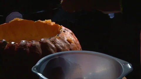 Cutting scooping meat from top cap of pumpkin into the plate Stock Footage