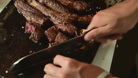 Cutting Seared Beef Strips into Cubes on Wooden Cutting Board for Cooking Stock Footage 340955764