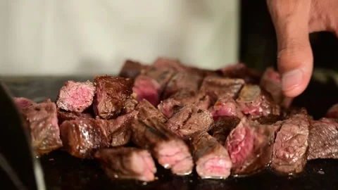 Cutting Seared Beef Strips into Cubes on Wooden Cutting Board for Cooking Stock Footage 340955995