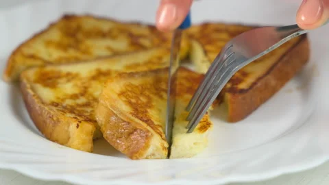 Cutting served fried toasts bread slices on plate to eat on kitchen at home. Stock Footage 313134775