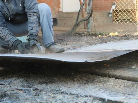 Cutting sheet metal with an angle grinder in the yard. Stock Photos