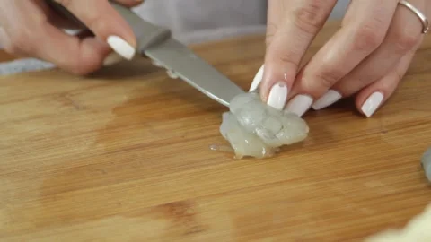 Cutting the shrimp in half. A womans hand uses a knife to cut a peeled shrimp Stock Footage 315028637