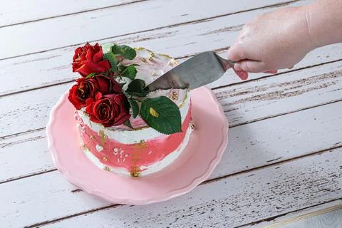 Cutting a slice of chocolate cake topped with Swiss meringue buttercream. Stock Photos