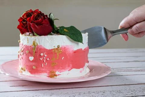 Cutting a slice of chocolate cake topped with Swiss meringue buttercream (sid Stock Photos