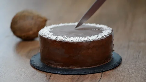 Cutting a slice of chocolate coconut cake Stock Footage 88732212