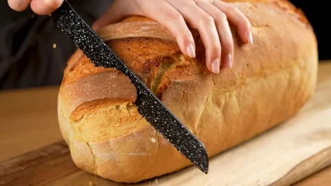 Cutting a slice of freshly baked bread with a serrate knife in slow motion 4K Stock Footage 266221820
