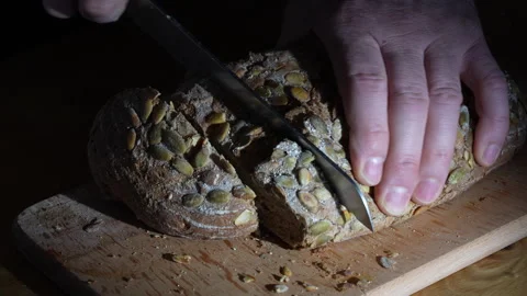 Cutting slice of homemade crusty bread with a sharp knife on wooden board Stock Footage 270218322