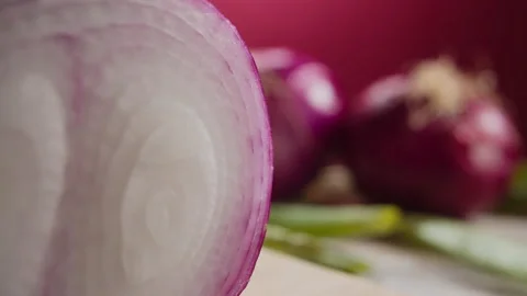 CUTTING A SLICE OF RED ONION ON PURPLE BACKDROP Stock Footage 132491317