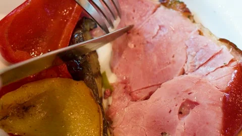 Cutting a Slice of Roasted Ham with Grilled Bell Peppers Stock Footage 334827873