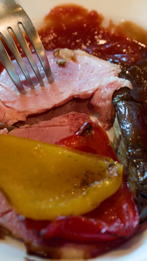 Cutting a Slice of Roasted Ham with Grilled Peppers on a Plate Stock Footage 334986954
