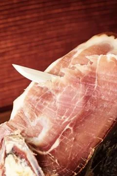 Cutting a slice of Spanish ham. Vertically. Stock Photos