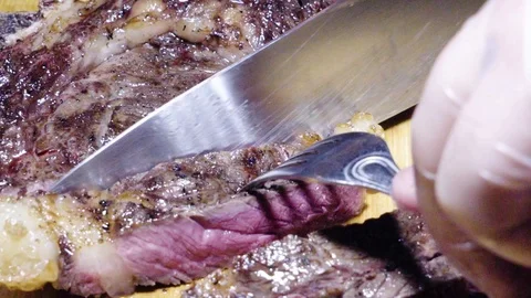 Cutting into slices of a big steak Stock Footage 115773320