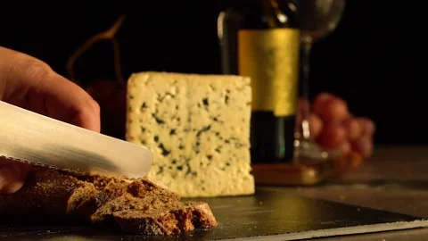 Cutting slices of wholemeal bread with cheese, wine and grapes. Stock Footage 169628465