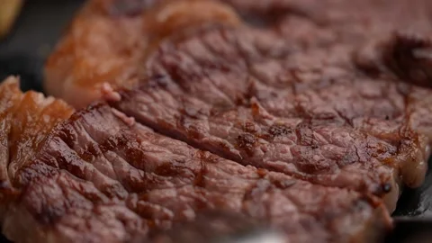 Cutting steak with knife and fork on black plate, slow motion 4k 120p Stock Footage 157992368