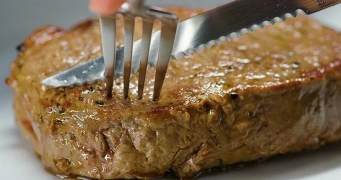 Cutting into a steak with a steak knife Stock Footage 99737819
