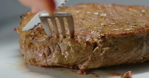 Cutting into a steak with a steak knife Stock Footage 99737999