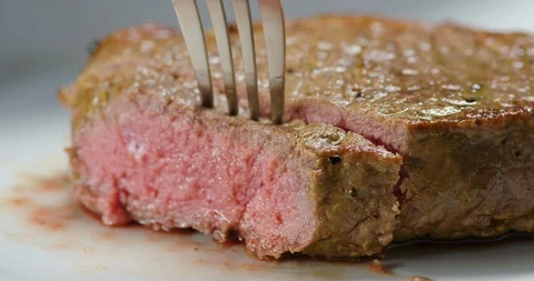 Cutting into a steak with a steak knife Stock Footage 99738142