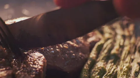 Cutting steak using a fork and knife close-up. Grill meat dish with vegetables Stock Footage 147375836