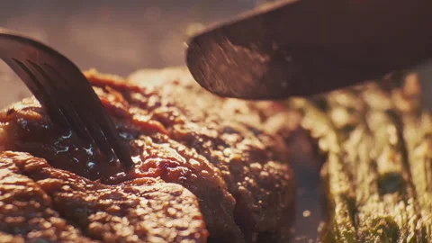 Cutting steak using a fork and knife close-up. Grill meat dish with vegetables Video stock 148692375