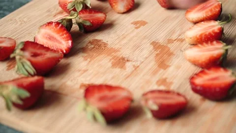 Cutting strawberries in half with a knife close up on a kitchen wooden Board Stock Footage 135605317
