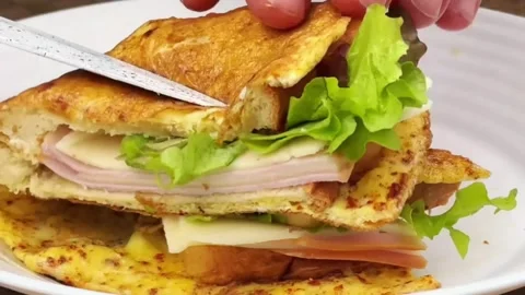 Cutting a stuffed egg omelette sandwich with a knife to show the fresh layers Stock Footage 324943396